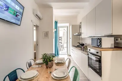 a kitchen with a wooden table and chairs and a kitchen with white cabinets at Nala Luxury Apartment with terrace in Rome