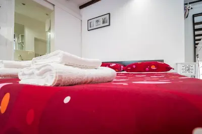 a red bed with white blankets and pillows on it at Apartment Gaia in Rome