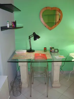 a glass table with a lamp and a desk with a laptop at La Casa Dei Gerani in Rome