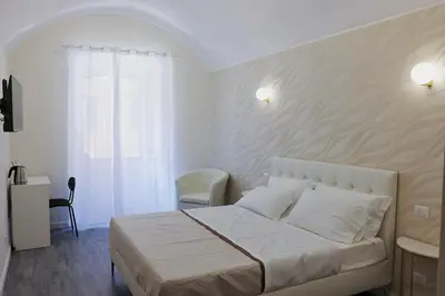 a white bedroom with a bed and a chair at Holiday 168 Guest House in Rome
