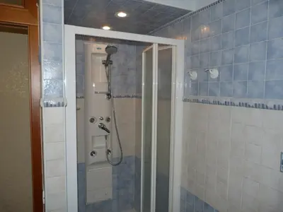 a shower in a bathroom with blue tiles at Rossanella House in Rome