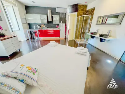 a large white bed in a room with a kitchen at Azadi Suite Flaminio in Rome