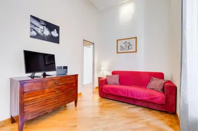 a living room with a red couch and a wooden dresser at Crescenzio St Peter’s House in Rome