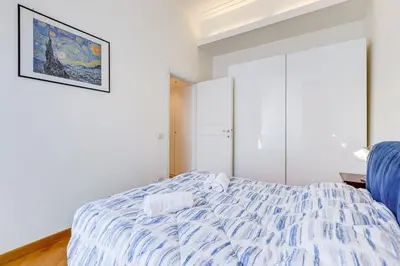a bedroom with a bed with a blue and white comforter at Crescenzio St Peter’s House in Rome