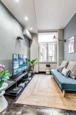 a living room with a blue couch and a tv at Daag Corso Luxury Apartment in Rome