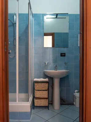 a blue tiled bathroom with a sink and a shower at Pura Vida in Rome