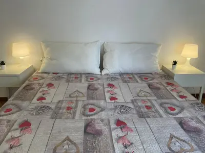 a bed with a quilt on it with two tables at Group Apartment Roma in Rome