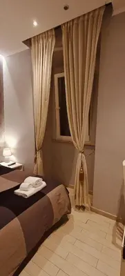 a bedroom with a bed and a window with curtains at ROMAnce Cosimato Trastevere B&B in Rome