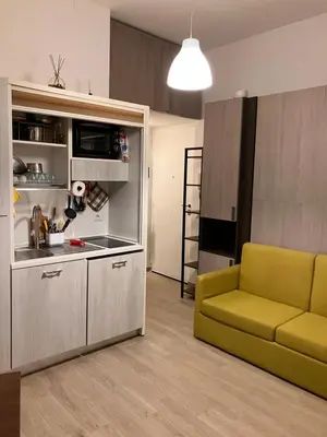 a living room with a yellow couch and a kitchen at The Green House in Rome