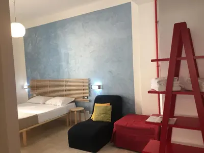 a bedroom with a bed and a chair and a ladder at Roma Art Rooms in Rome