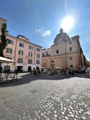 a group of buildings in a plaza with the sun in the sky at Nest to Colosseum in Rome