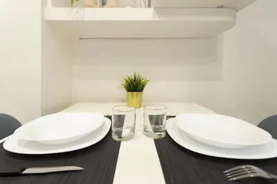 a table with two white plates and glasses on it at Nina - Tiny Suite in Trastevere in Rome