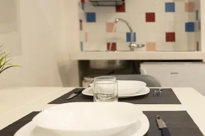 a table with plates and a glass of water on it at Nina - Tiny Suite in Trastevere in Rome