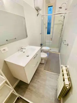 a white bathroom with a sink and a toilet at Mamisà Rome, appartamento con parcheggio privato e gratuito in Rome