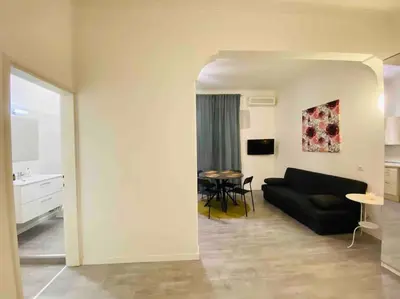 a living room with a black couch and a table at Mamisà Rome, appartamento con parcheggio privato e gratuito in Rome