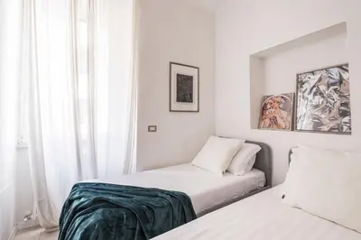a white bedroom with two beds and a window at The Best Rent - Bright flat near San Pietro in Rome