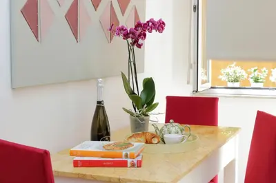 a table with a bottle of wine and a vase of flowers at NuvolHouse in Rome