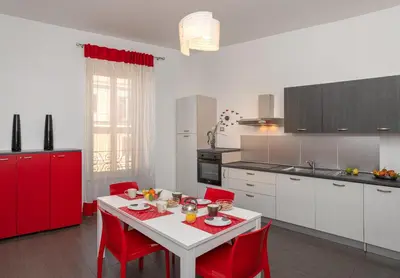 a kitchen with a white table and red chairs at Suite Deal in Rome