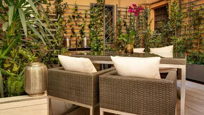 a patio with wicker chairs and a table with plants at Domus Domitia Luxury Living in Rome