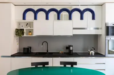 a kitchen with white cabinets and blue accents at ROMAC Trinity with steam bath in Rome