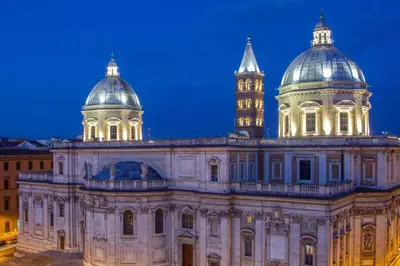 a building with domes and a clock tower at night at Daplace - Virginia Apartment in Rome