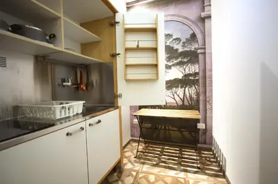 a kitchen with white cabinets and a table in it at Monti Holiday House in Rome