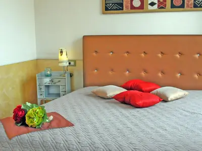 a bed with red pillows and a bouquet of flowers on it at Aldebaran in Rome