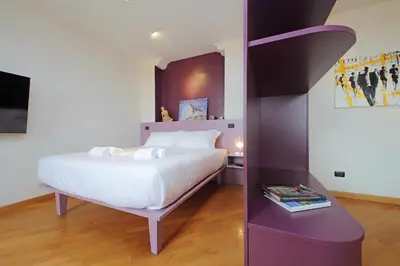 a bedroom with a white bed and a purple wall at suity I monkeys apartment in Rome