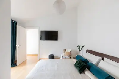 a white bedroom with a large bed with blue pillows at Barberini Caesar Suites in Rome