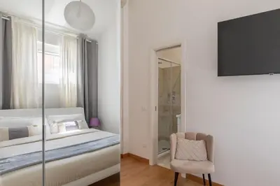 a bedroom with a bed and a chair and a tv at Barberini Caesar Suites in Rome