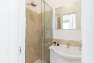 a bathroom with a shower and a sink and a mirror at Barberini Caesar Suites in Rome