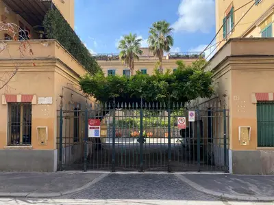 a gate to a building with palm trees behind it at Cortile al Vaticano by Bed&Bros in Rome