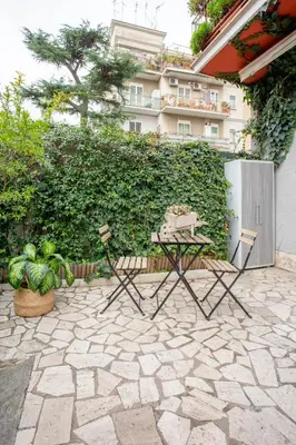 a patio with a white door and a green hedge at Holiday Homes Rome - Portuense 21 - Studio with little private Garden in Rome