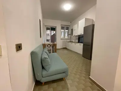a living room with a blue couch and a kitchen at Casa Sofia Trastevere in Rome