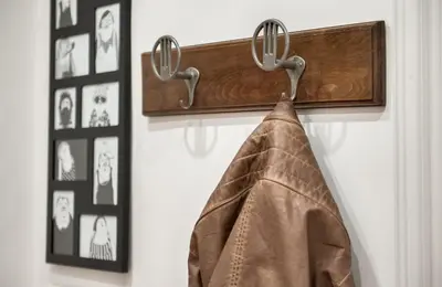 a brown jacket hanging on a coat rack with pictures at Appartamento con giardino via silvestri in Rome
