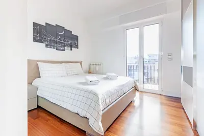 a white bedroom with a bed and a large window at 15 Minuti a Piedi dai Musei Vaticani in Rome