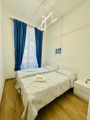 a bedroom with two beds and blue curtains at Casa Vacanza Kambal in Rome