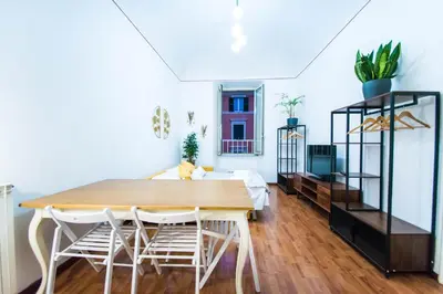a dining room with a wooden table and white chairs at Tibullo House in Rome