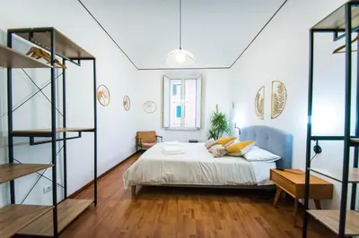 a bedroom with a bed with white walls and wooden floors at Tibullo House in Rome
