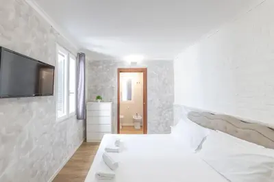 a white bedroom with a bed and a tv on a wall at Domus Augustea - 2 Floor in Rome