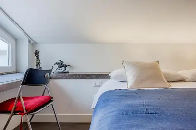 a bedroom with a bed and a red chair at Casa Doni Roma in Rome