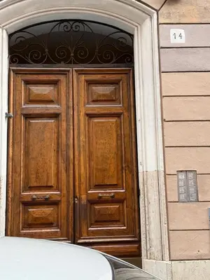 a wooden door on a building with a car in front at sweety rome in Rome
