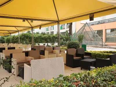 a patio with tables and chairs under a yellow umbrella at Vatican City Green Apartment in Rome