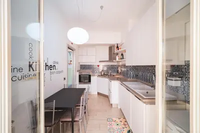 a kitchen with white cabinets and a black counter top at Tiber House 60 Rome Marconi - Rome Vacation M&D in Rome
