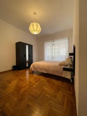 a bedroom with a bed and wooden floors and a chandelier at MySweetHome near the Vatican in Rome