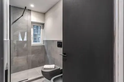 a bathroom with a shower and a toilet and a glass door at Suite Orsoline Spanish steps in Rome