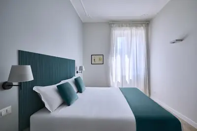 a bedroom with a white bed with green and white pillows at Domus Modista (Musei Vaticani) in Rome