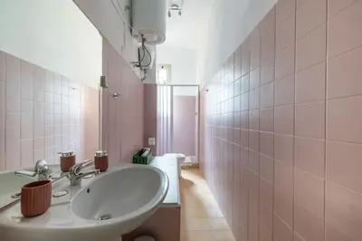 a bathroom with a sink and a pink tiled wall at San Lorenzo Residence two in Rome