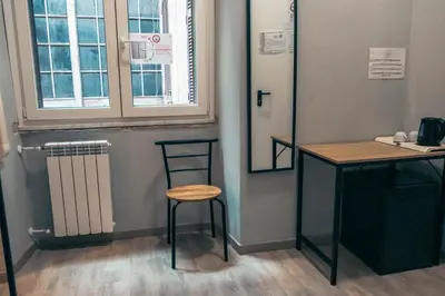 a stool next to a table and a window at Eureka Rooms in Rome