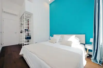a white bed in a room with a blue wall at Fontana di Trevi dream home in Rome